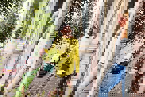 Onder de pannen foto 2 personen bij een woning